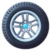a car tire with blocky tread mounted on a spoked wheel